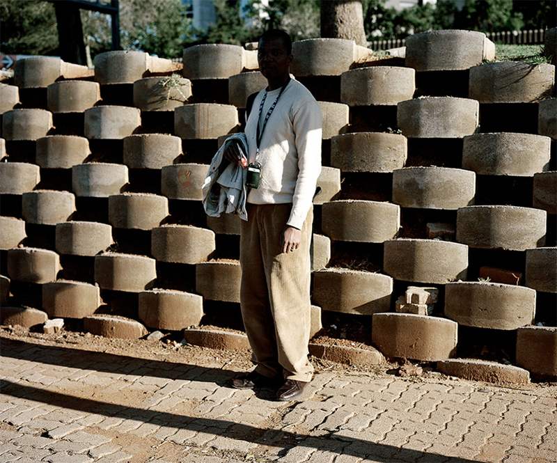 Photographed in South Africa, a man stands in the shade, sheltering from the intense heat