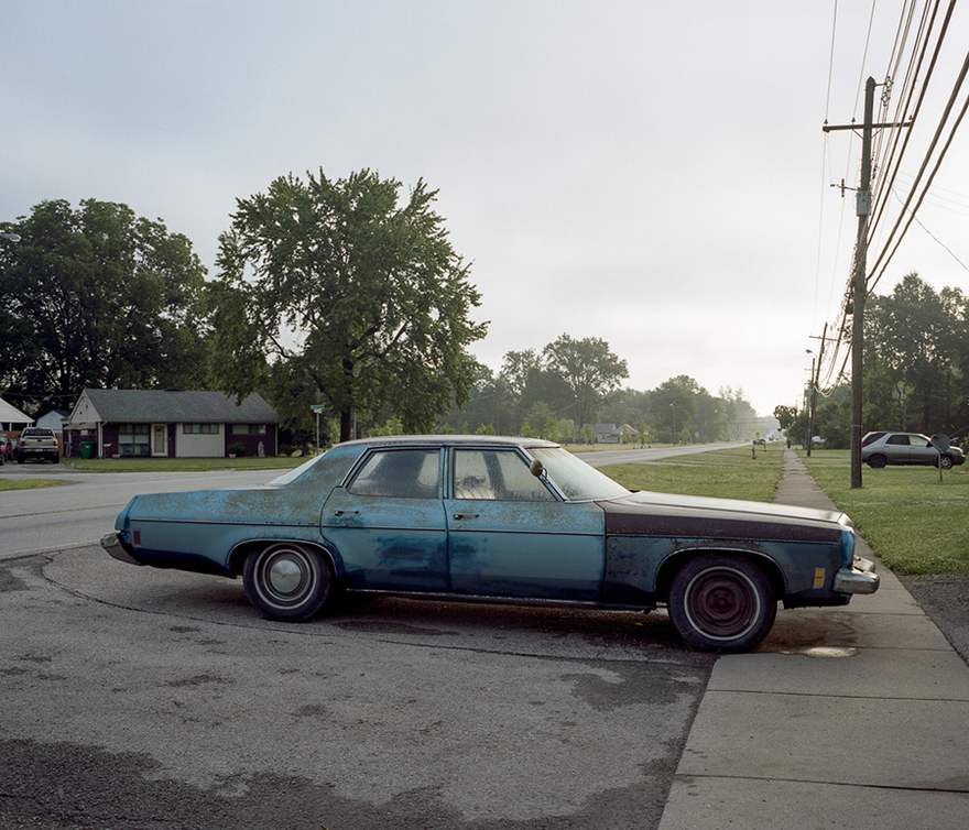 An old blue sedan car, which is parked