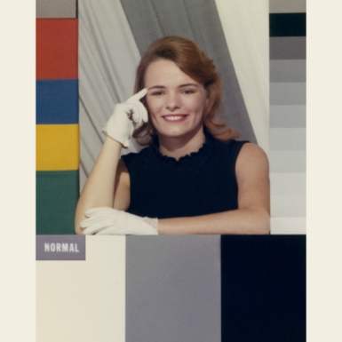 A 'colour girl' card. A test card with a white woman wearing a black dress and white gloves, surrounded by colour reference bars.