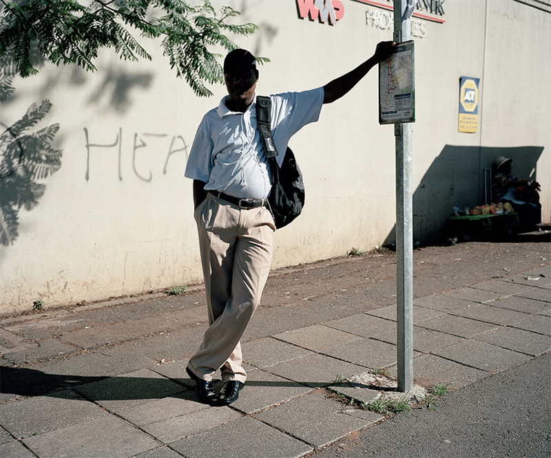 Photographed in South Africa, a man stands in the shade, sheltering from the intense heat