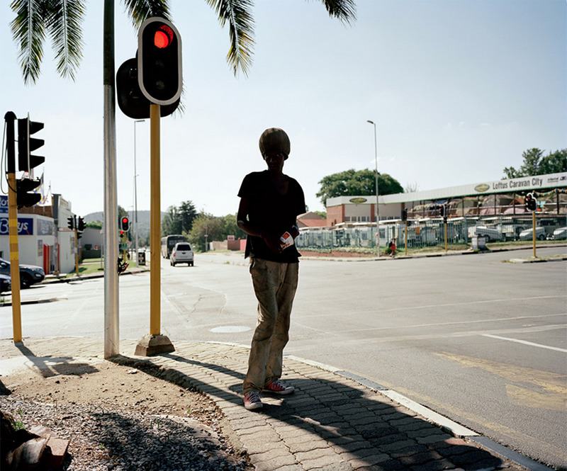 Photographed in South Africa, a man stands in the shade, sheltering from the intense heat