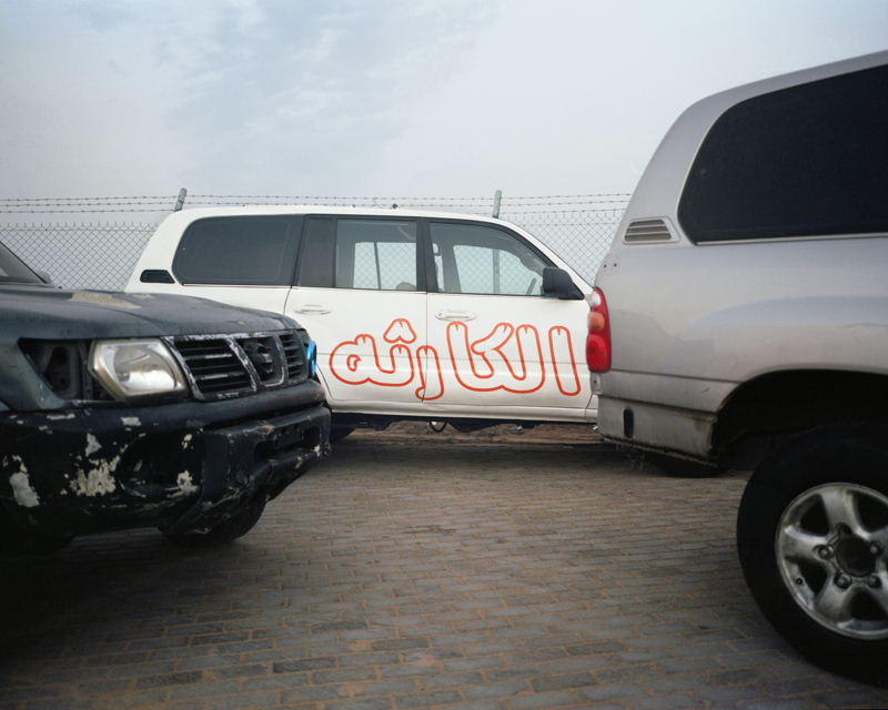 Cars line up on the side of a drifting meet in Umm Al Quwain, UAE. The decal reads "disaster," the name of a crew of drivers.