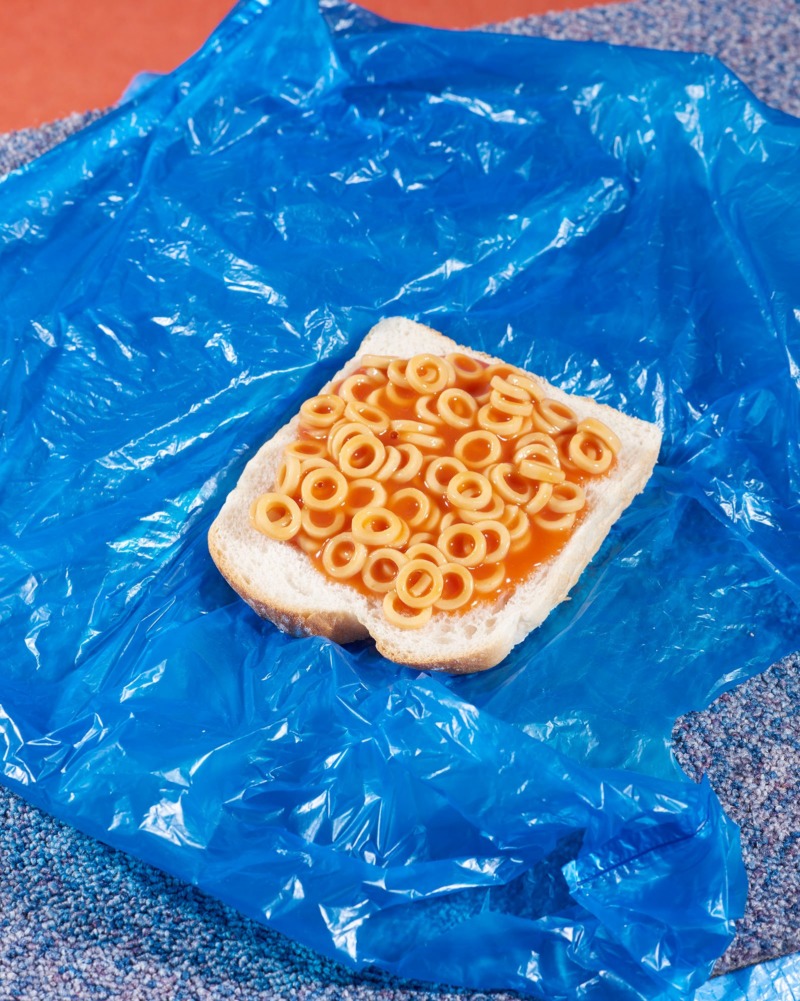A photograph of spaghetti hoops on bread, laid on a blue plastic bag.