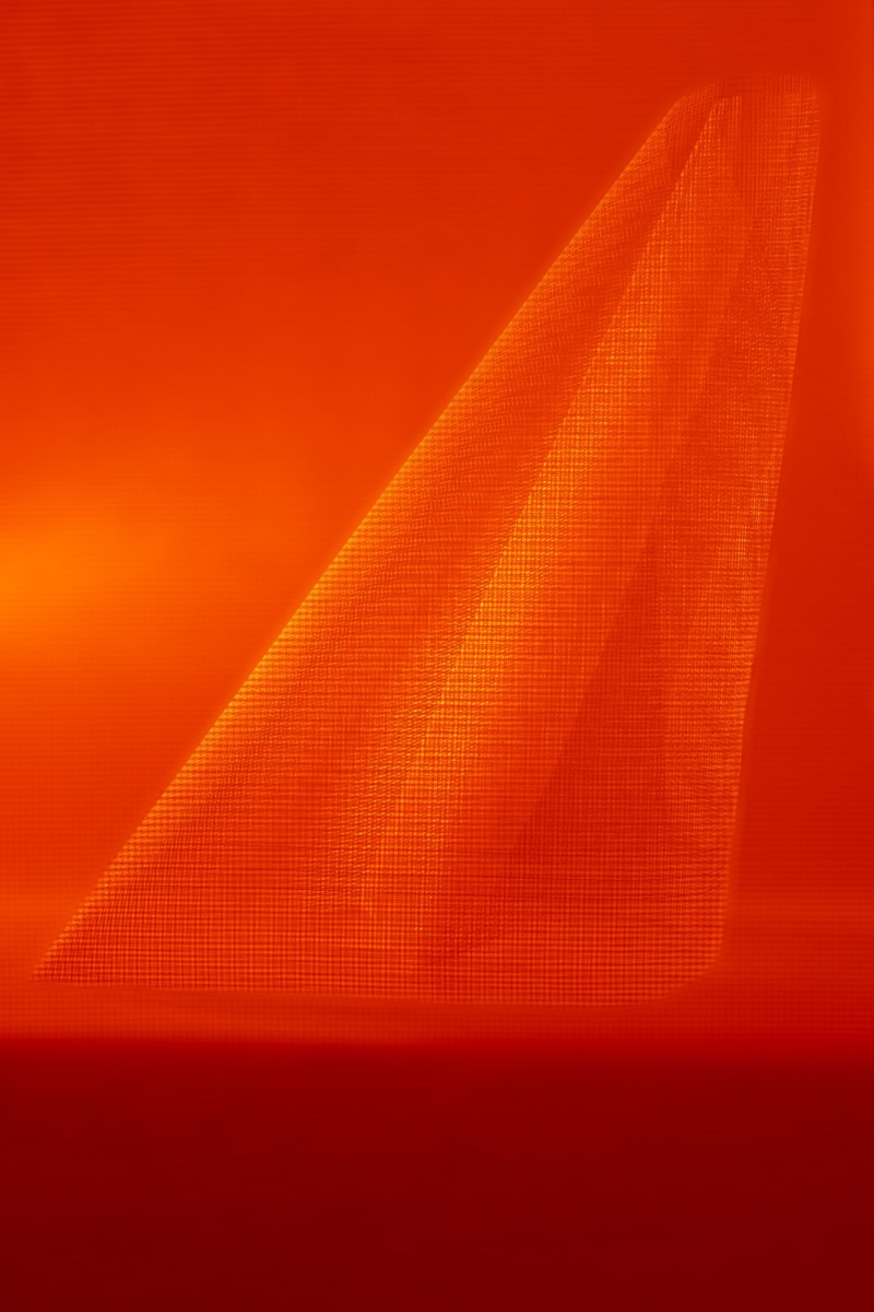 A fine mesh is pleated, creating a strange shape in the red light.