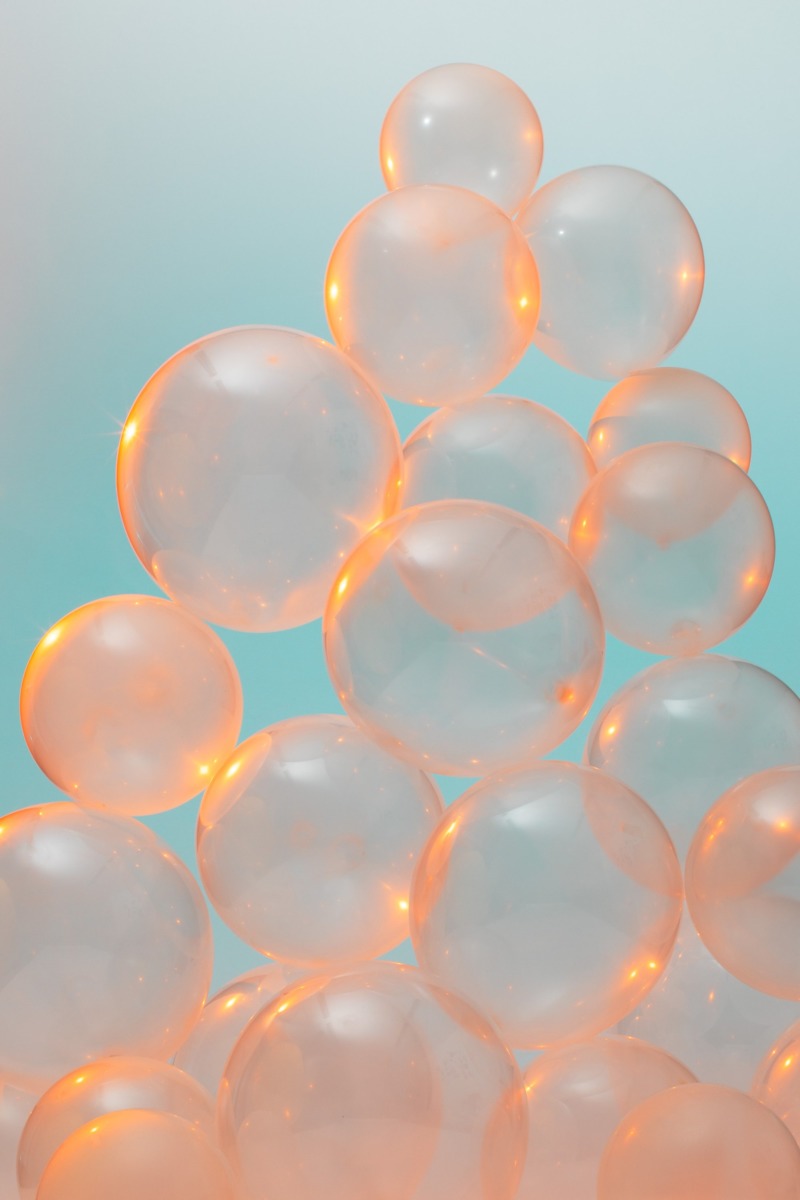 The picture is filled with translucent balloons against a pale blue background, lit by a warm orange glow.