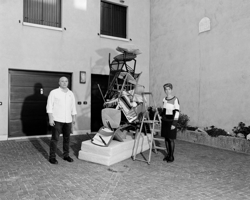 Agostini's parents stand by a pile of chairs nad tables.