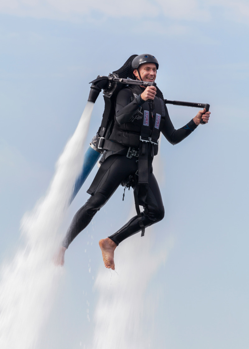 A man soars through the air on a water jetpack.