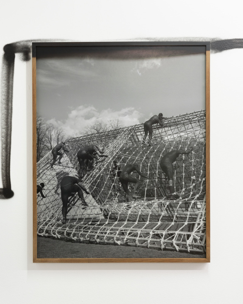 A framed photographe of workers climbing a netted pile of bags.