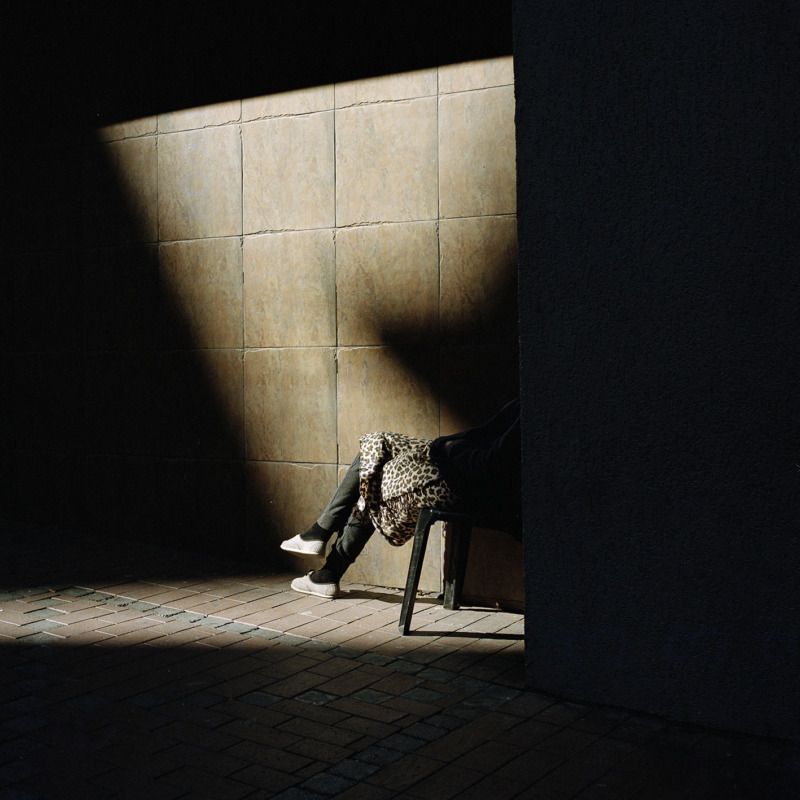 In a quiet corner, a person sits in a shaft of light.