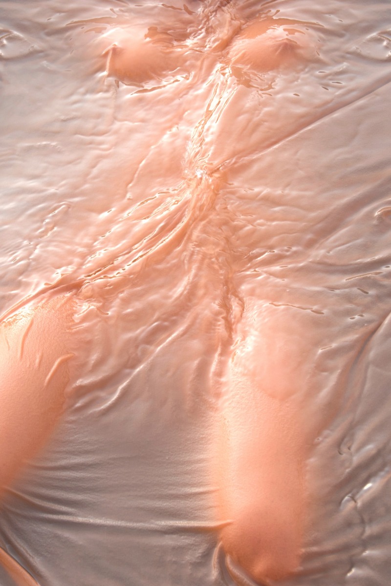 A shimmering nude floats beneath the surface of the water.