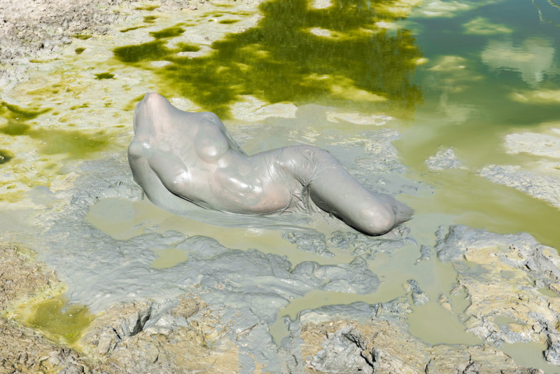 A headless torso poses seductively in a pearlescent pool.