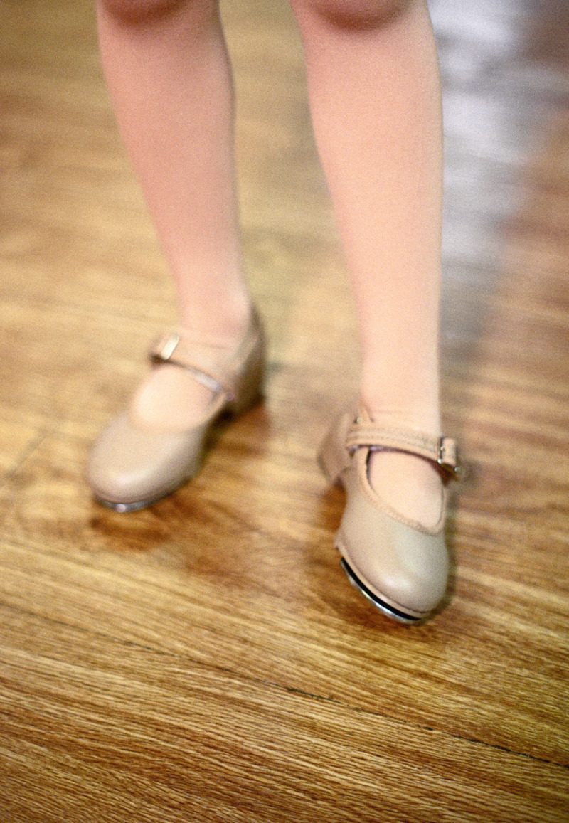 A photograph of a young girl standing anxiously in a tap dance studio.